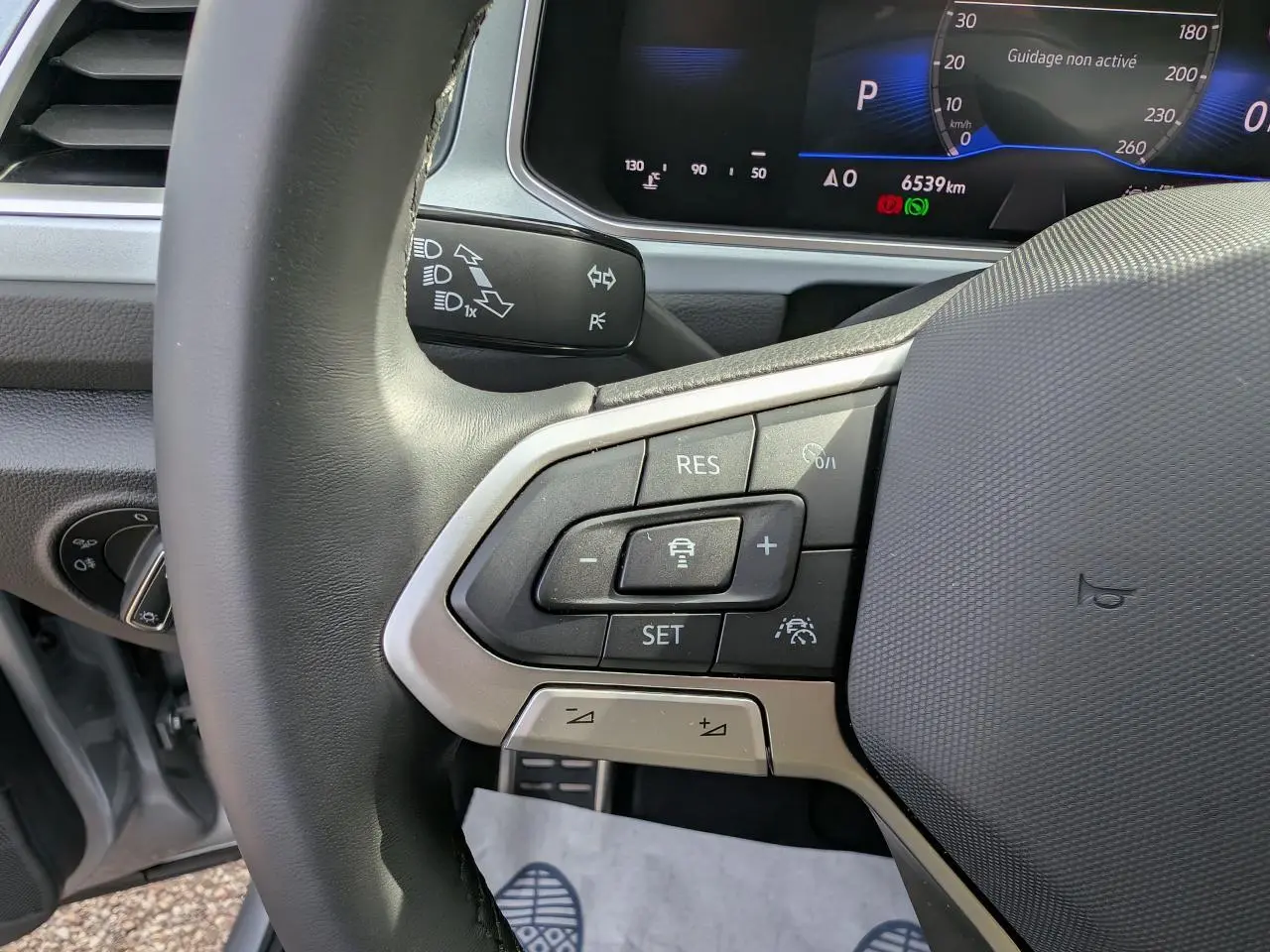 Gros plan sur le volant côté gauche du Volkswagen T-Roc gris 2025, avec commandes du régulateur adaptatif visibles.