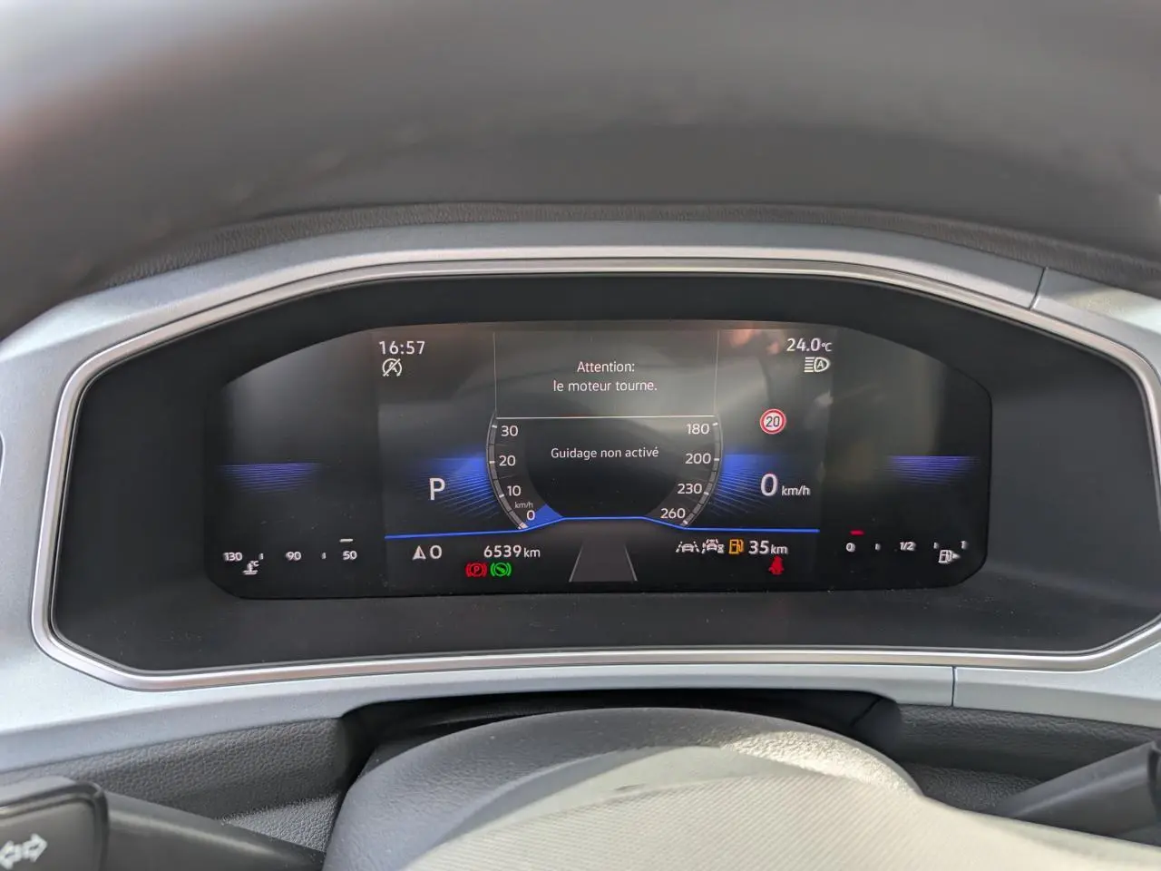 Vue rapprochée du tableau de bord digital du Volkswagen T-Roc gris, affichant la vitesse et alertes moteur.