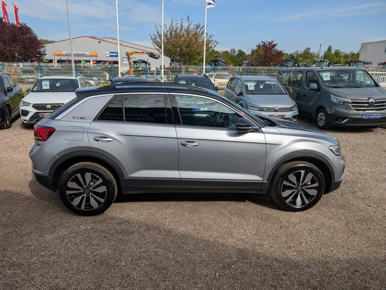 Profil droit d'un Volkswagen T-Roc gris métallisé avec jantes alliage 17 pouces et toit noir, stationné en extérieur.