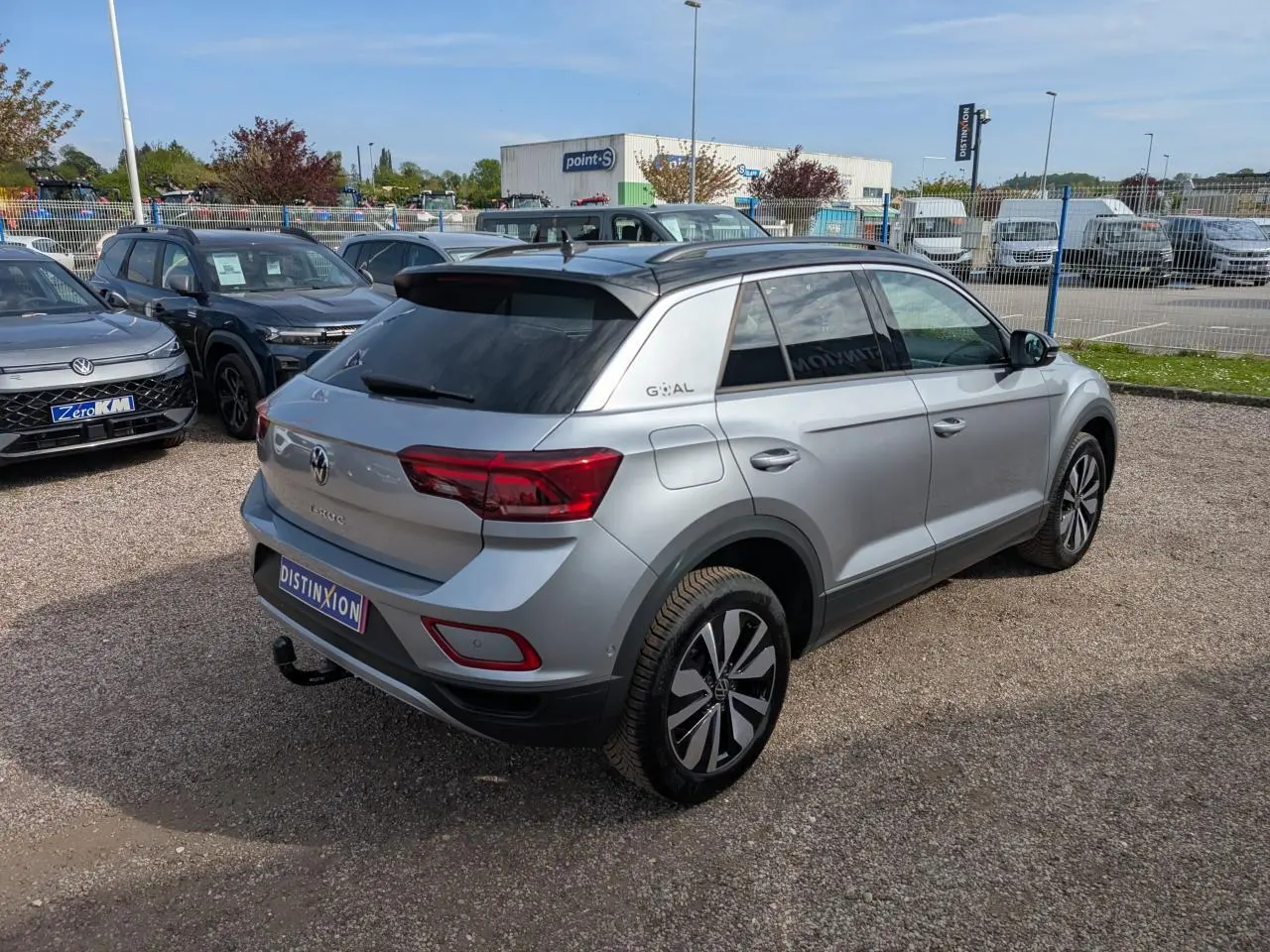 Vue 3/4 arrière droite d'un Volkswagen T-Roc gris métallisé avec toit noir et attelage amovible visible.