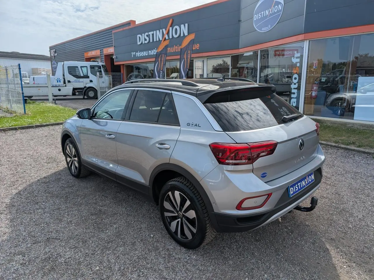 Volkswagen T-Roc gris vue 3/4 arrière droit avec toit noir et attelage amovible visible.