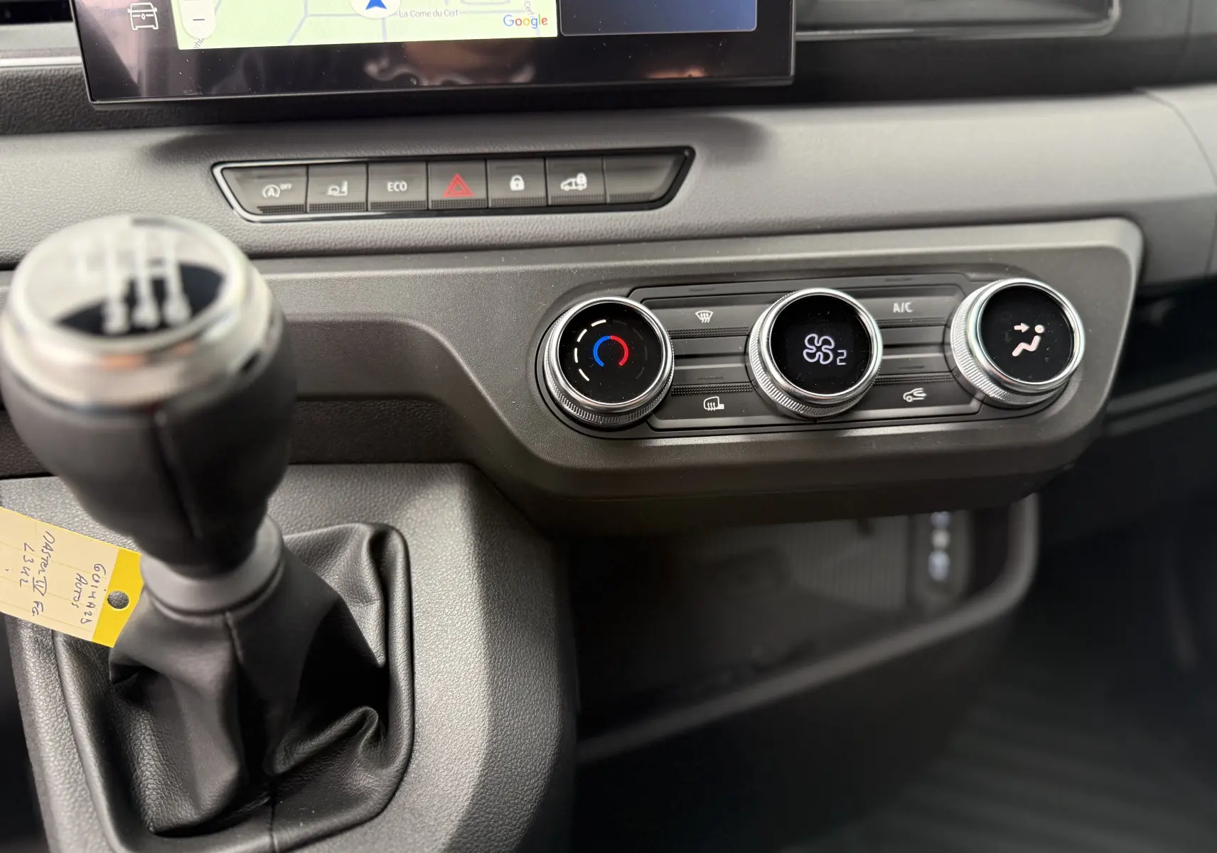 Gros plan sur la console centrale noire nacrée du Renault Master 2024, avec levier de vitesse manuel et commandes de climatisation.