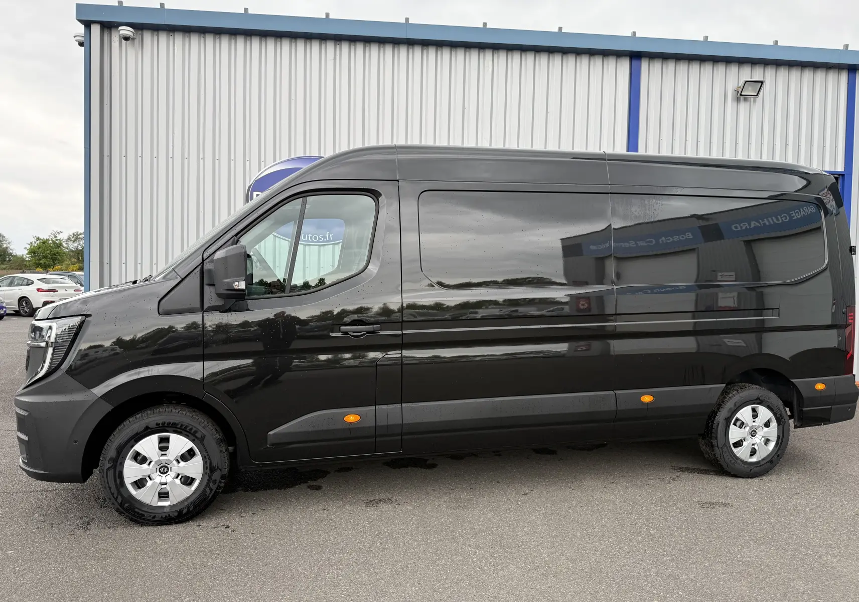 Profil côté gauche d'un Renault Master noir nacré 2024, fourgon long avec feux latéraux orange et jantes argentées.