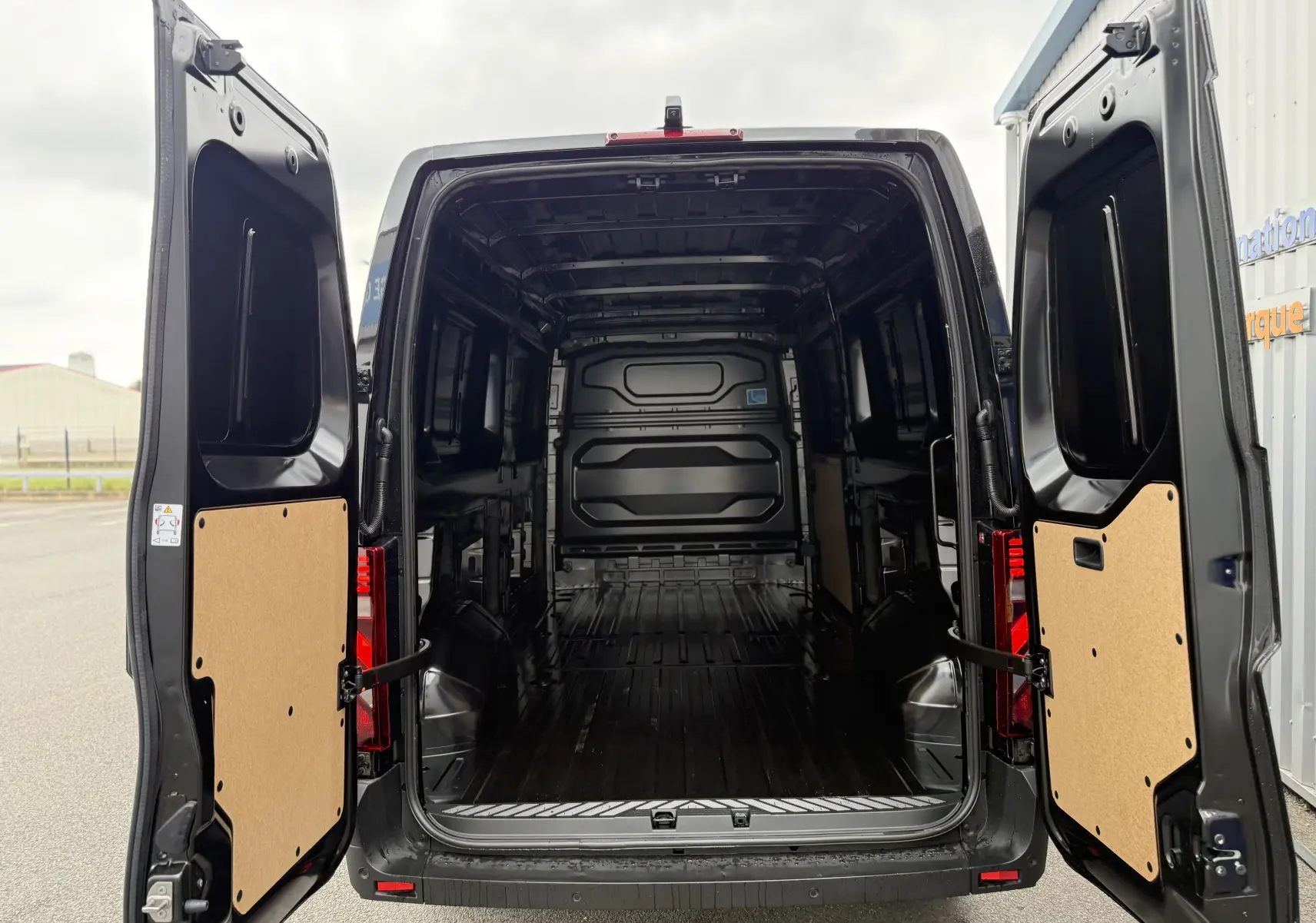 Vue arrière du Renault Master noir nacré 2024 avec portes ouvertes dévoilant un grand espace de chargement vide.