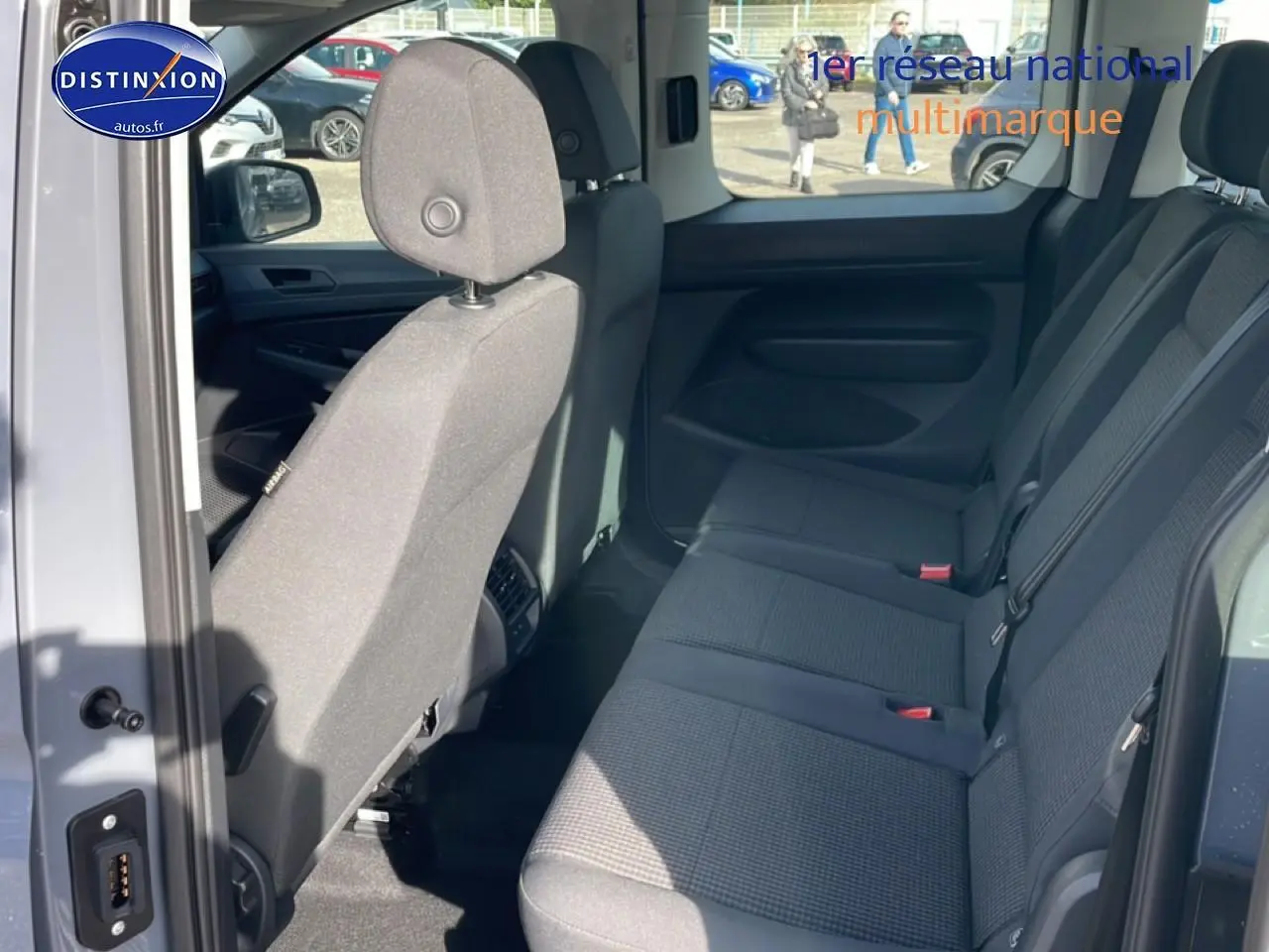 Vue intérieure côté droit du Volkswagen Caddy 2025 gris pur, montrant la banquette arrière trois places en tissu noir titane.