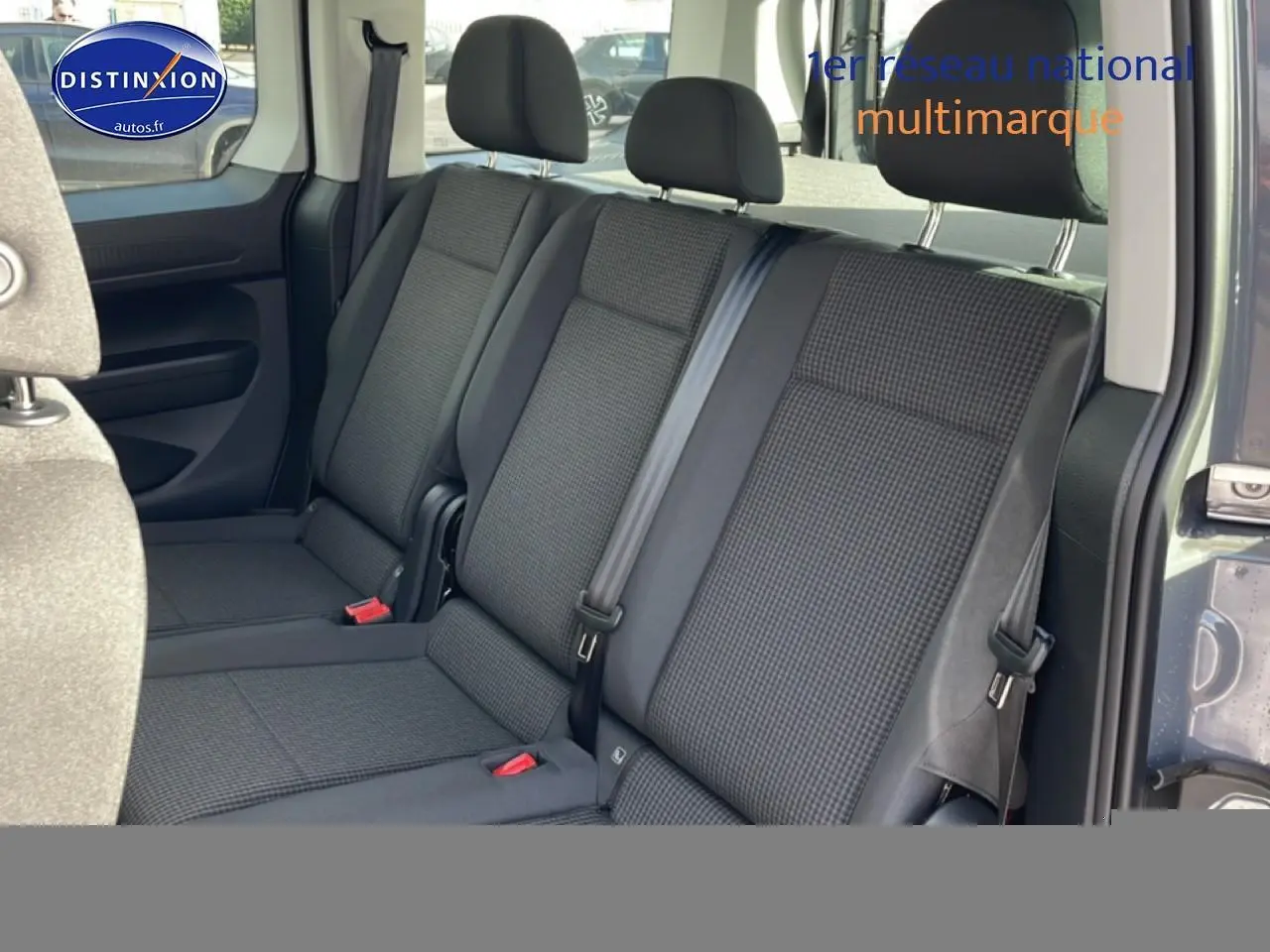 Vue intérieure côté droit sur la banquette arrière en tissu noir à motif double grid du Volkswagen Caddy gris pur 2025.