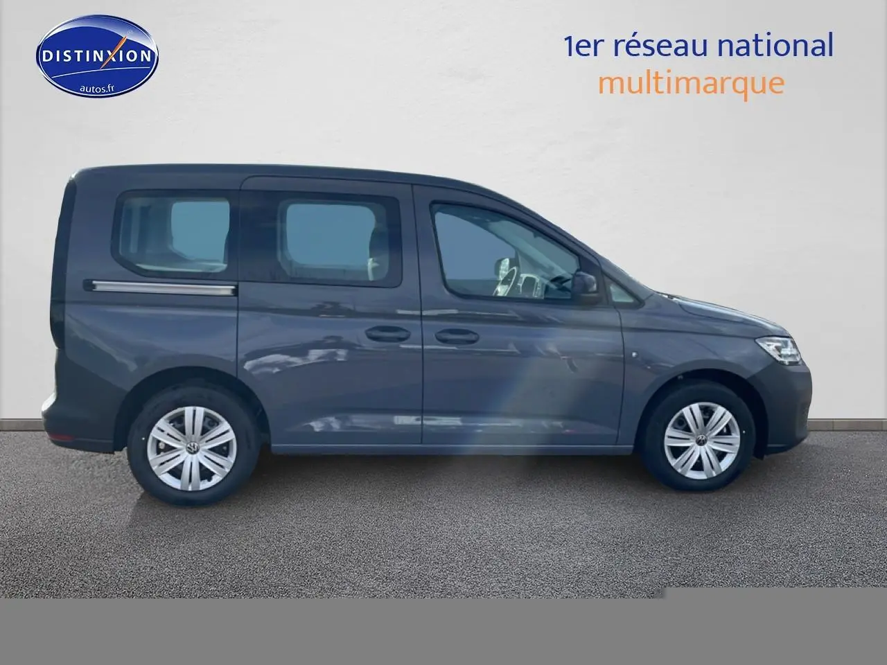 Profil latéral droit d'un Volkswagen Caddy gris pur 2025 avec vitres teintées et jantes alliage.