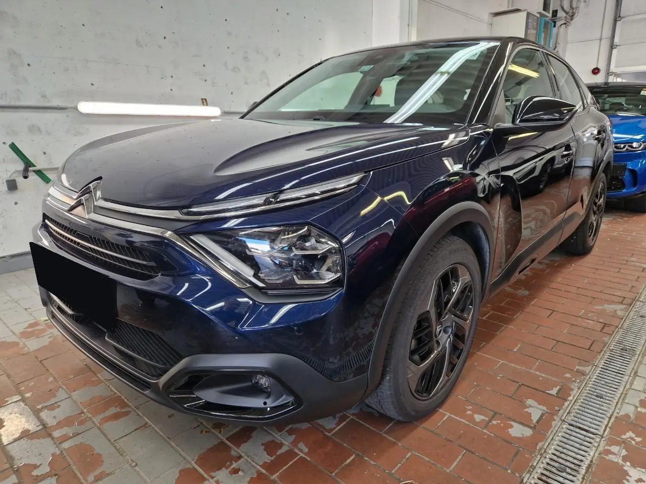 Citroën C4 2024 bleu Eclipse en 3/4 avant droit, avec toit noir et jantes alliage 18 pouces distinctives.