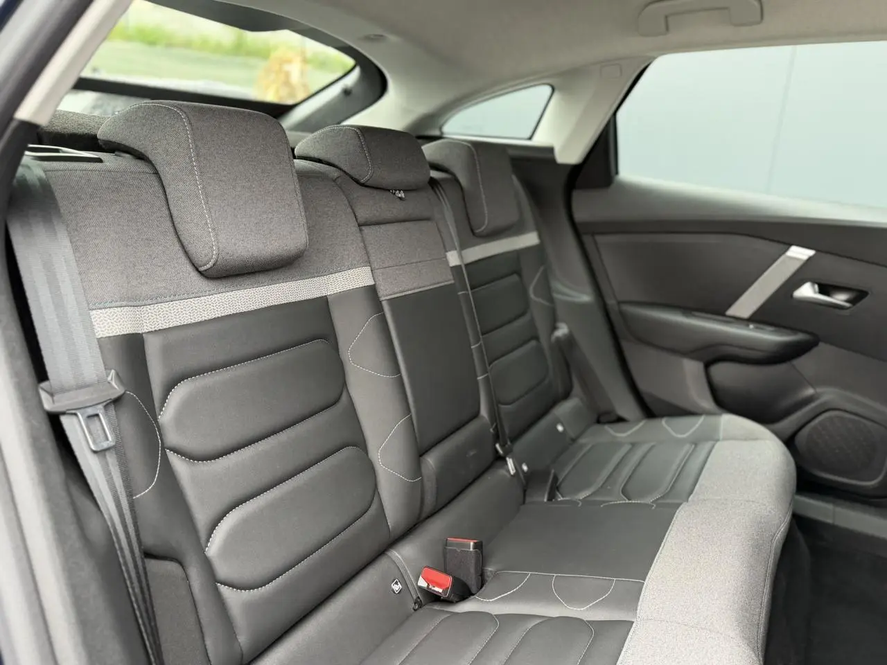 Vue latérale droite de la banquette arrière gris et noir avec appuie-têtes et ceintures visibles du Citroën C4 2024.