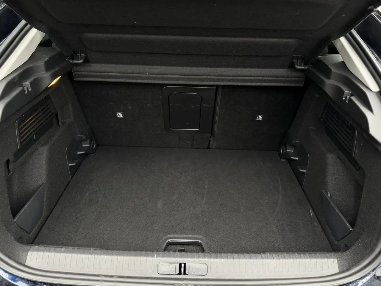 Coffre ouvert vu de l'arrière du Citroën C4 2024 Bleu Eclipse avec intérieur noir et trappe à skis centrale.