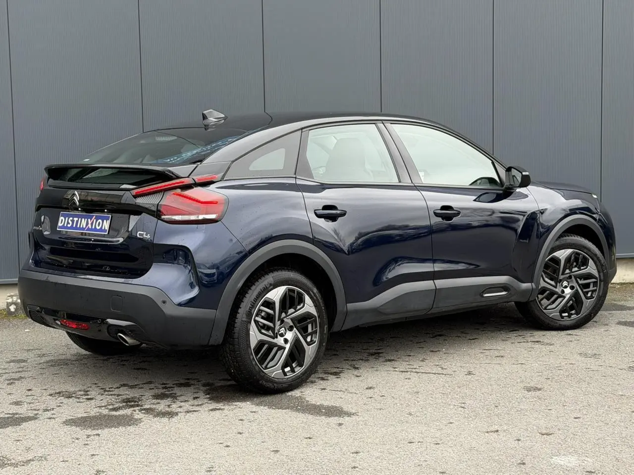 Vue 3/4 arrière droite d'une Citroën C4 2024 bleu Eclipse avec toit noir et jantes alliage 18 pouces.