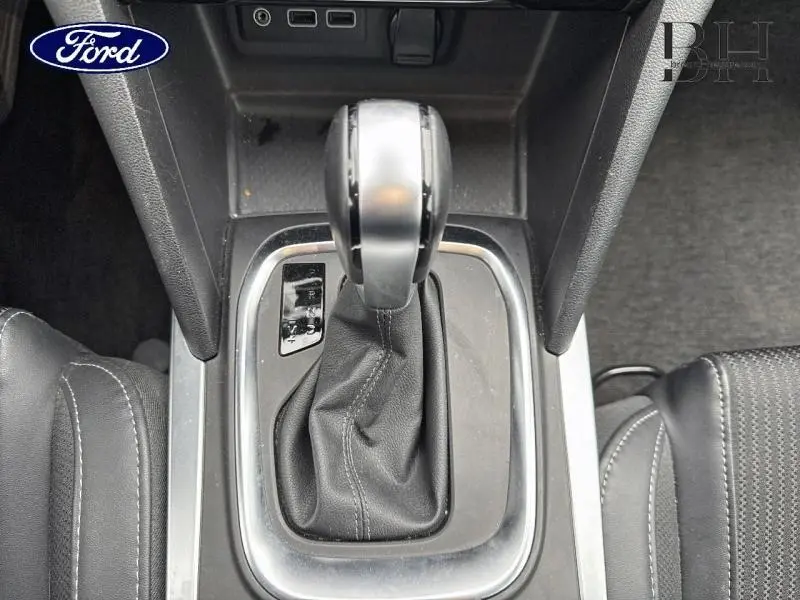 Vue rapprochée du levier de vitesses automatique noir et argenté dans l'habitacle d'une Renault Mégane blanche.