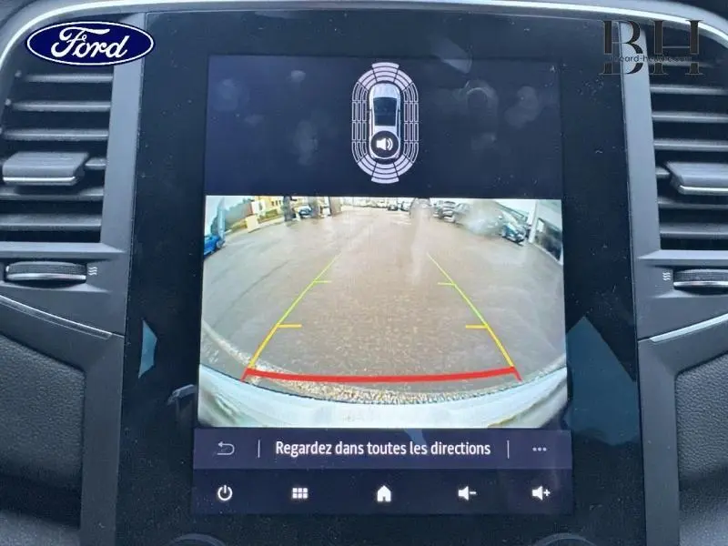 Écran tactile intérieur montrant la caméra de recul avec guidage dynamique d’une Renault Mégane blanche.