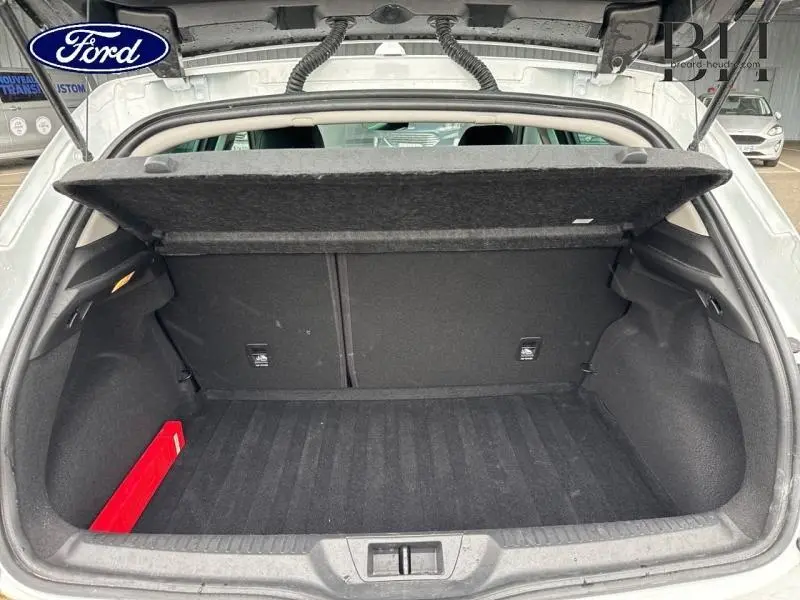 Coffre ouvert vu de l'arrière d'une Renault Mégane blanche, avec cache-bagages relevé et intérieur noir.