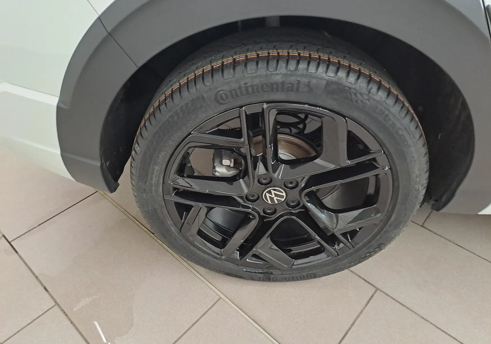 Gros plan sur la roue arrière droite du Volkswagen Taigo blanc pur, jante alliage noir brillant R-Line Edition.