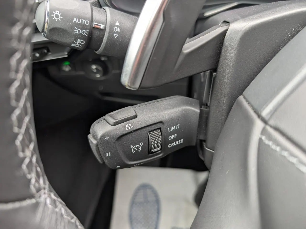 Gros plan sur la commande de régulateur de vitesse noir dans l’habitacle du DS7 2024, côté gauche du volant.