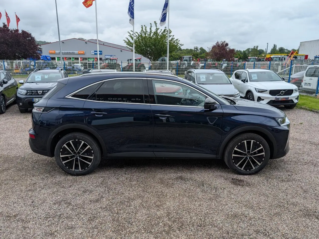 Profil côté gauche du SUV DS7 2024 bleu saphir métallisé avec jantes alliage noires et toit noir.