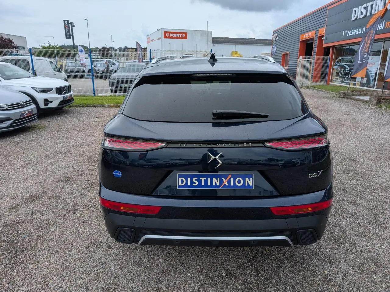 Vue arrière d'un DS7 bleu métallisé avec feux arrière 3D et logo DS Automobiles sur un parking extérieur.