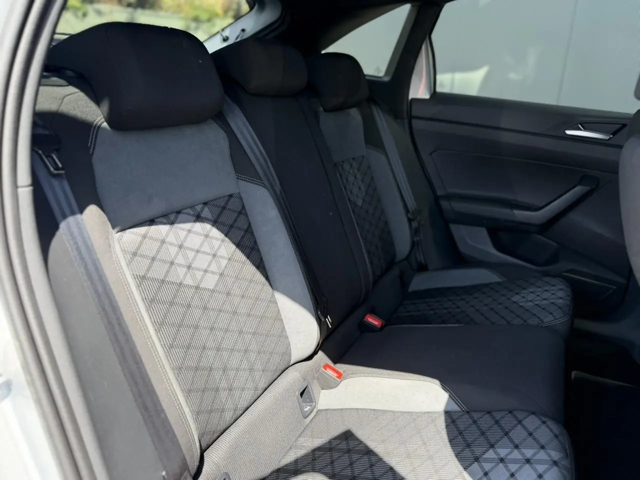 Vue intérieure de la banquette arrière du Volkswagen Taigo TSI 116 DSG R-Line, sellerie tissu noir et gris à motifs géométriques.