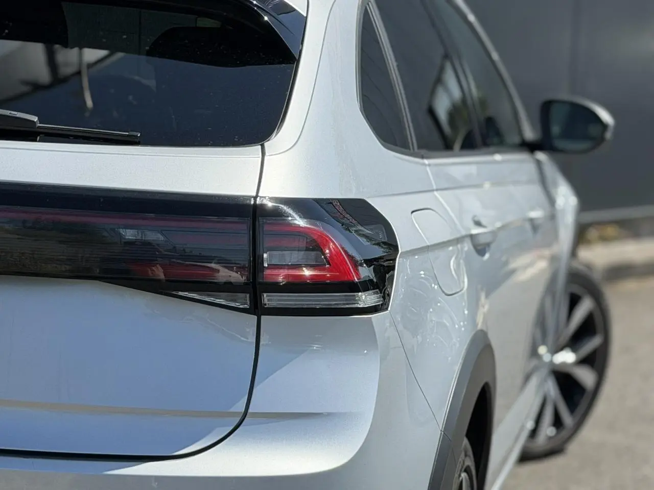 Vue arrière côté droit d’un Volkswagen Taigo TSI 116 DSG R-Line argent Reflex avec feux arrière LED et jantes alliage 18 pouces.