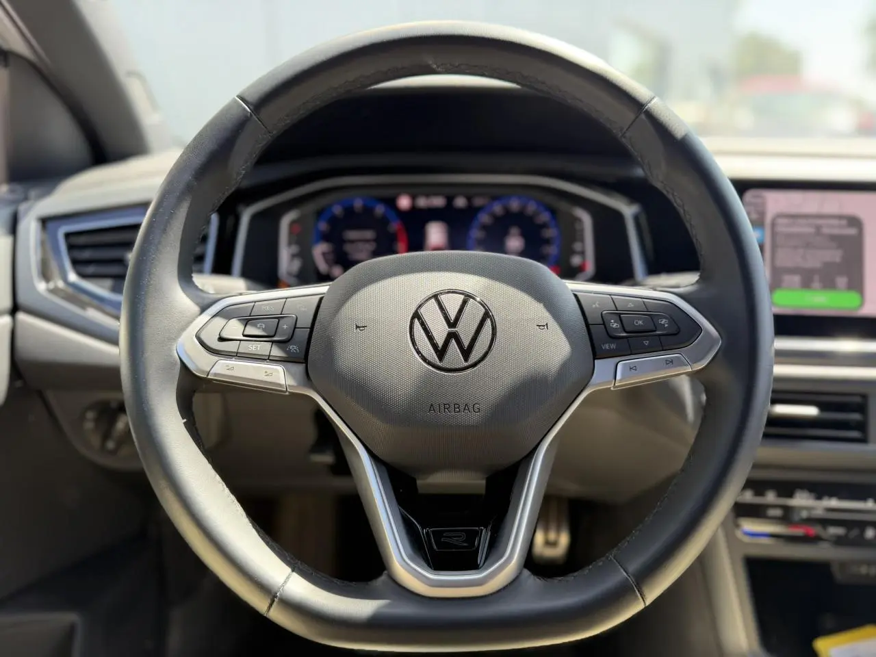 Vue rapprochée du volant cuir multifonctions Volkswagen Taigo TSI 116 DSG R-Line avec logo R et tableau de bord numérique.