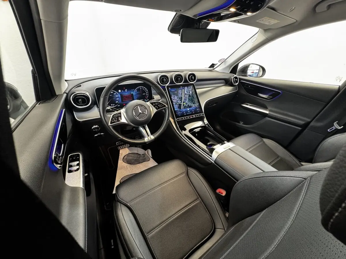 Vue intérieure avant droite du Mercedes GLC 300 E Business Line 2023, sièges cuir noirs et écran tactile central lumineux.