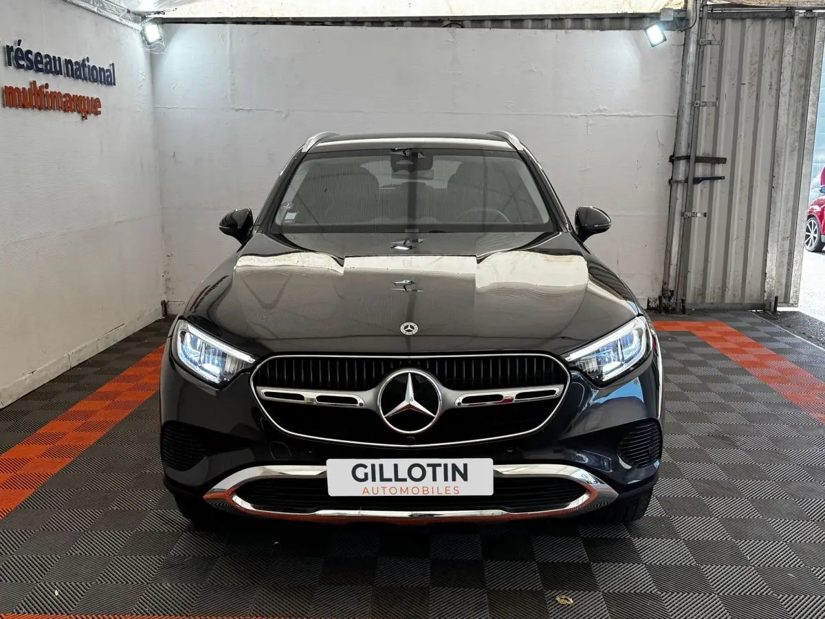 Vue frontale d'un Mercedes GLC 300 E Business Line 4MATIC gris foncé avec calandre chromée et phares LED allumés.