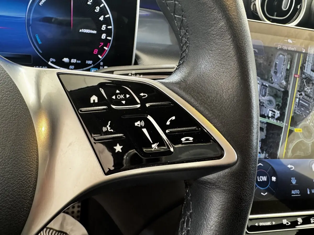 Gros plan sur le volant cuir noir et les commandes tactiles du Mercedes GLC 300 E Business Line 2023, écran tactile visible.