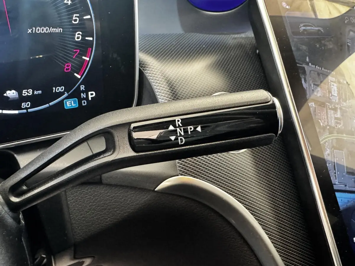 Gros plan sur la commande de boîte automatique noire dans l’habitacle du Mercedes GLC gris foncé, avec tableau de bord numérique visible.