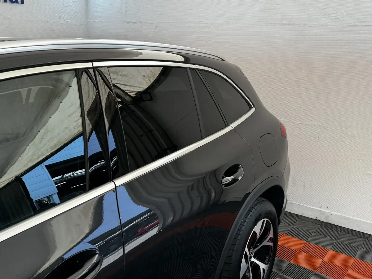 Vue latérale arrière droite d'un Mercedes GLC 300 E Business Line 4MATIC gris foncé avec jante alliage et vitres teintées.