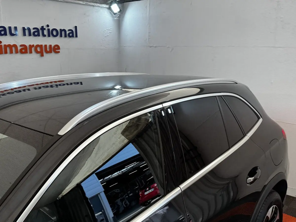 Vue latérale droite d’un Mercedes GLC 300 E Business Line gris foncé avec vitres teintées et barres de toit chromées.