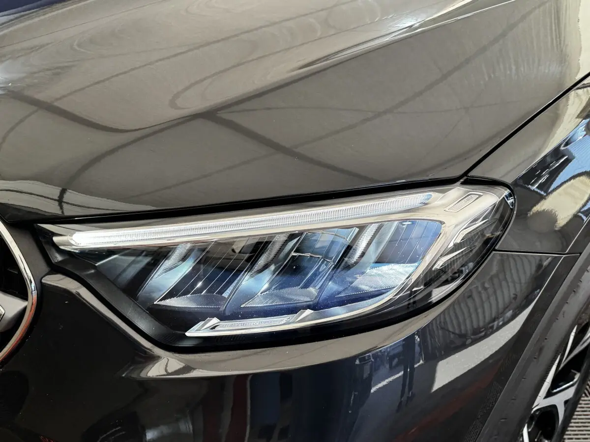 Gros plan sur le phare avant droit du Mercedes GLC 300 E Business Line gris foncé, avec détails LED visibles.