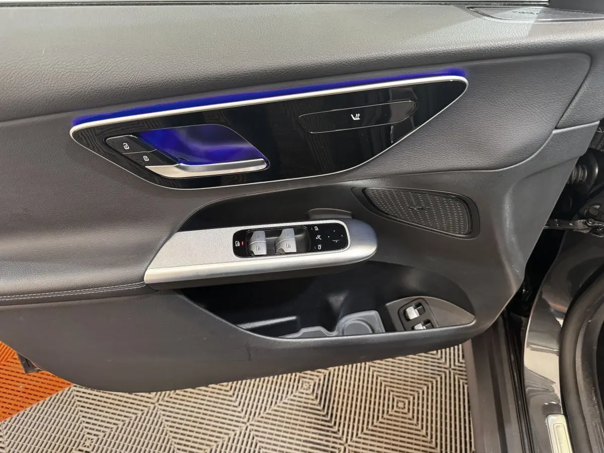 Vue rapprochée de la porte avant gauche du Mercedes GLC gris foncé avec commandes de vitres et éclairage d’ambiance bleu.