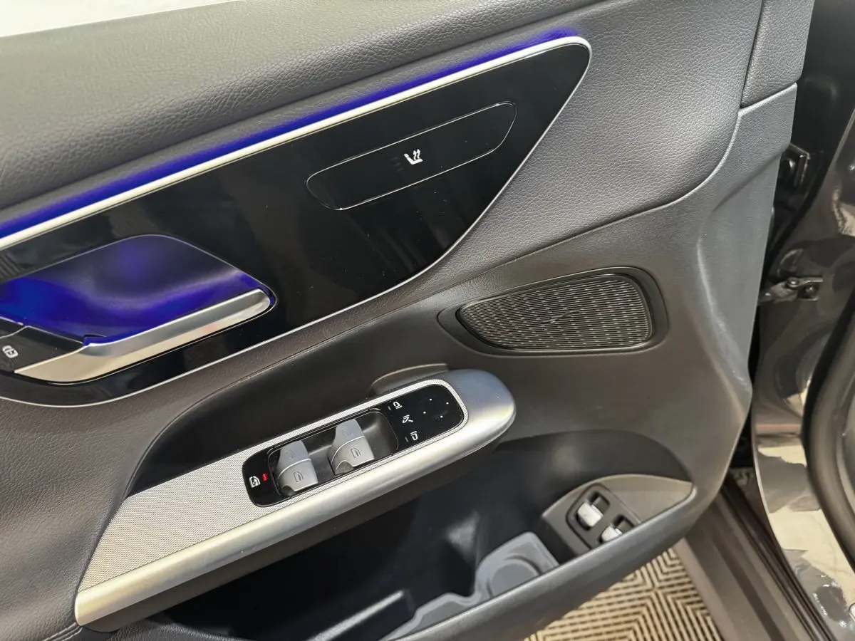 Détail de la porte avant gauche du Mercedes GLC 300 E Business Line 2023 gris foncé, avec commandes de vitres et éclairage d'ambiance bleu.