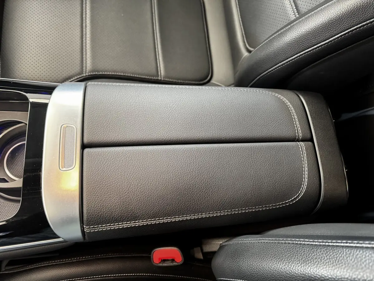 Vue rapprochée de l'accoudoir central en cuir noir avec surpiqûres blanches dans un Mercedes GLC 300 e Business Line 2023.