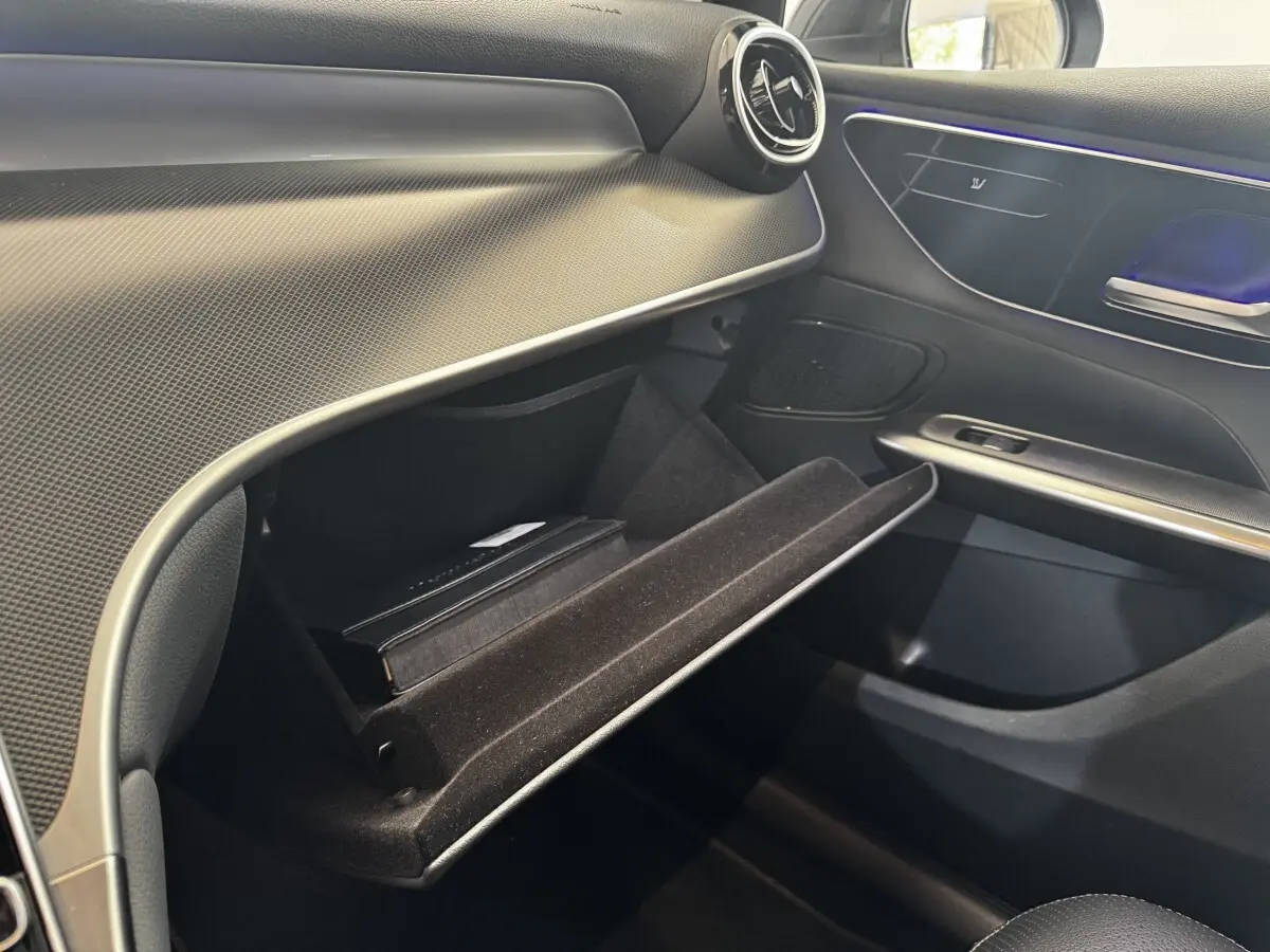Vue intérieure côté passager du Mercedes GLC 300 E Business Line 2023, boîte à gants ouverte avec livret à l'intérieur.