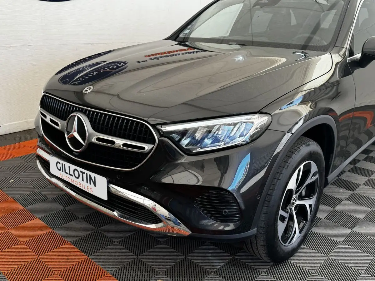 Vue 3/4 avant droit d'un Mercedes GLC 300 E Business Line hybride rechargeable gris foncé avec calandre chromée et phares LED.