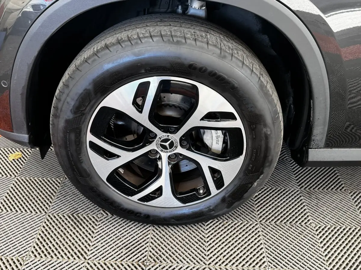 Gros plan sur la roue avant droite d’un Mercedes GLC gris foncé avec jante alliage bicolore et logo central étoile.