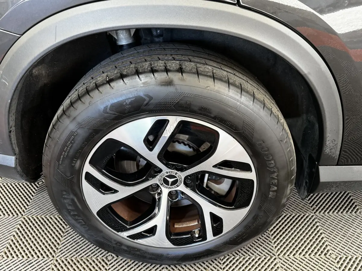 Gros plan sur la roue avant droite d’un Mercedes GLC gris foncé avec jante alliage bicolore et pneu Goodyear.