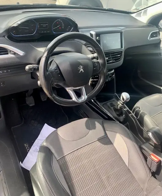 Intérieur du Peugeot 2008 2015 gris, vue côté conducteur montrant volant, tableau de bord et levier de vitesses manuel.