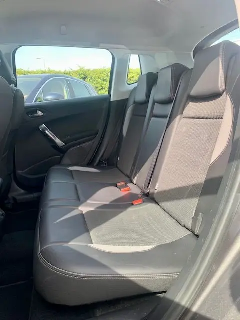 Banquette arrière en cuir noir du Peugeot 2008 gris, vue côté droit avec ceinture de sécurité rouge visible.