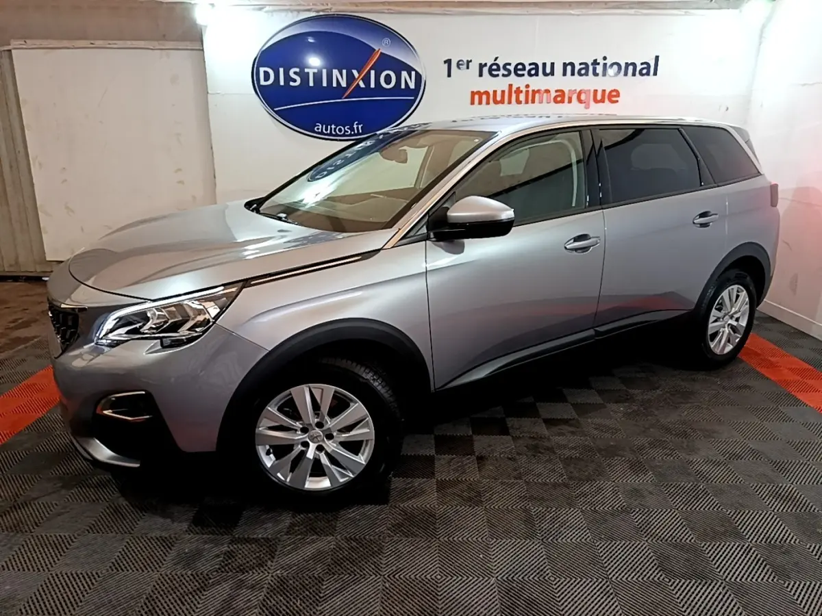 Peugeot 5008 gris foncé vue de profil droit en intérieur, mettant en valeur ses lignes modernes et ses jantes alliage.