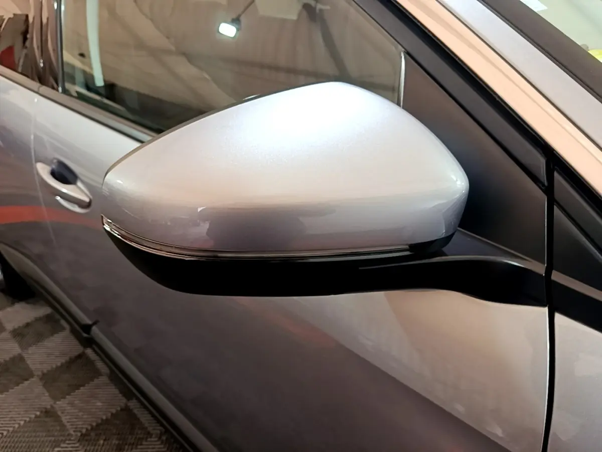 Gros plan sur le rétroviseur électrique gris clair du côté conducteur d’un Peugeot 5008 gris foncé.