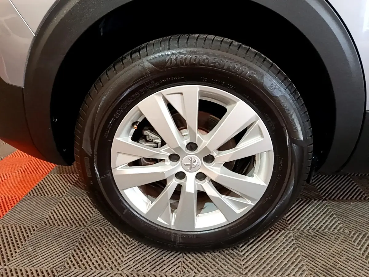 Gros plan sur la roue avant droite du Peugeot 5008 gris foncé avec jante alliage et pneu Bridgestone.