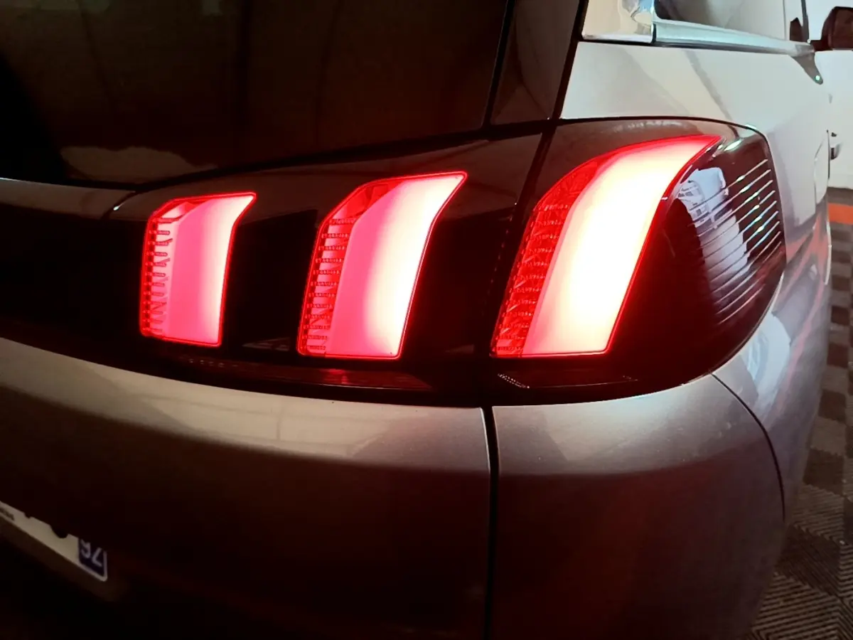Gros plan sur le feu arrière droit allumé d’un Peugeot 5008 gris foncé, soulignant ses trois griffes lumineuses distinctives.
