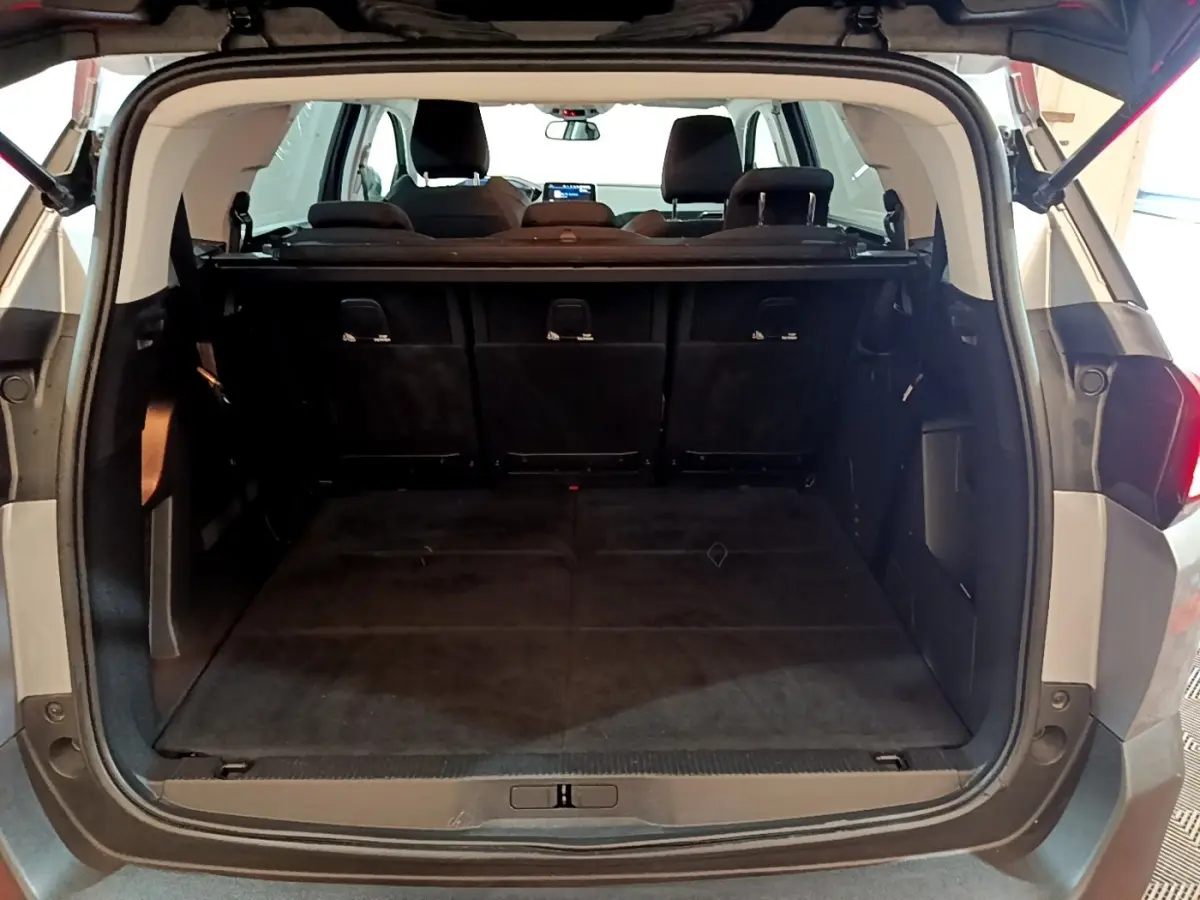 Coffre ouvert vu de l'arrière d'un Peugeot 5008 gris foncé, montrant la banquette arrière et l'espace de chargement.