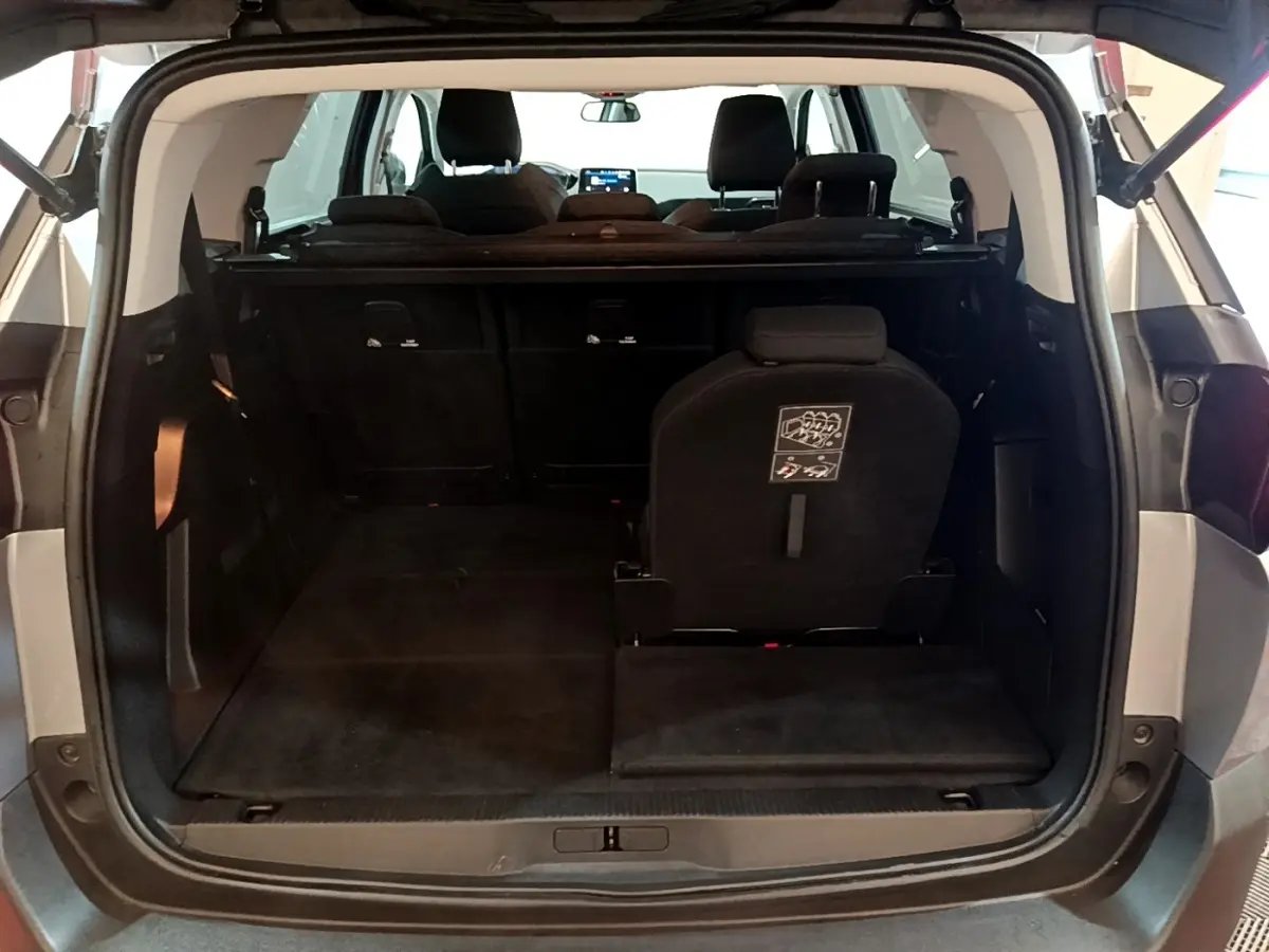 Vue arrière du coffre ouvert du Peugeot 5008 gris foncé, montrant la troisième rangée de sièges rabattables.