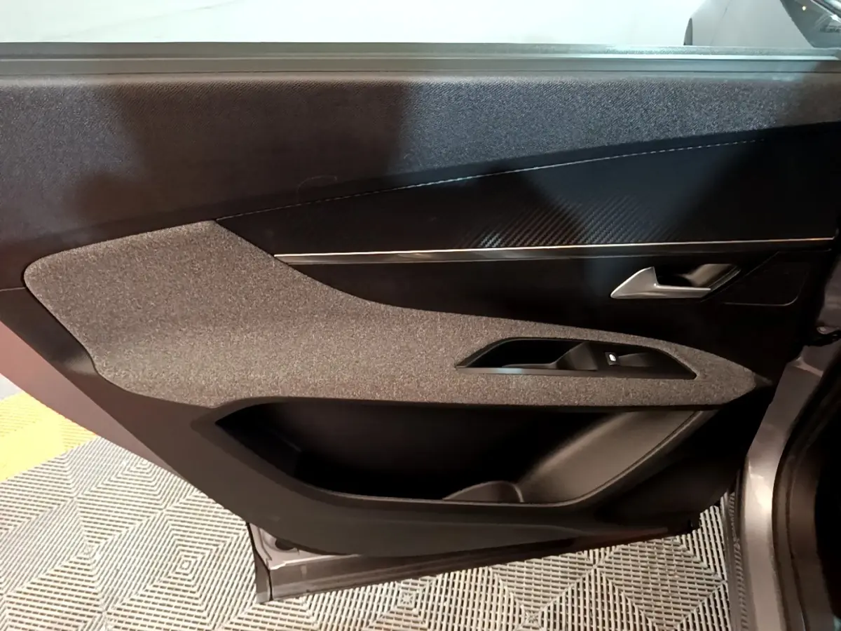 Vue intérieure du panneau de porte côté droit gris foncé du Peugeot 5008 avec insert décoratif noir et commande de vitre.