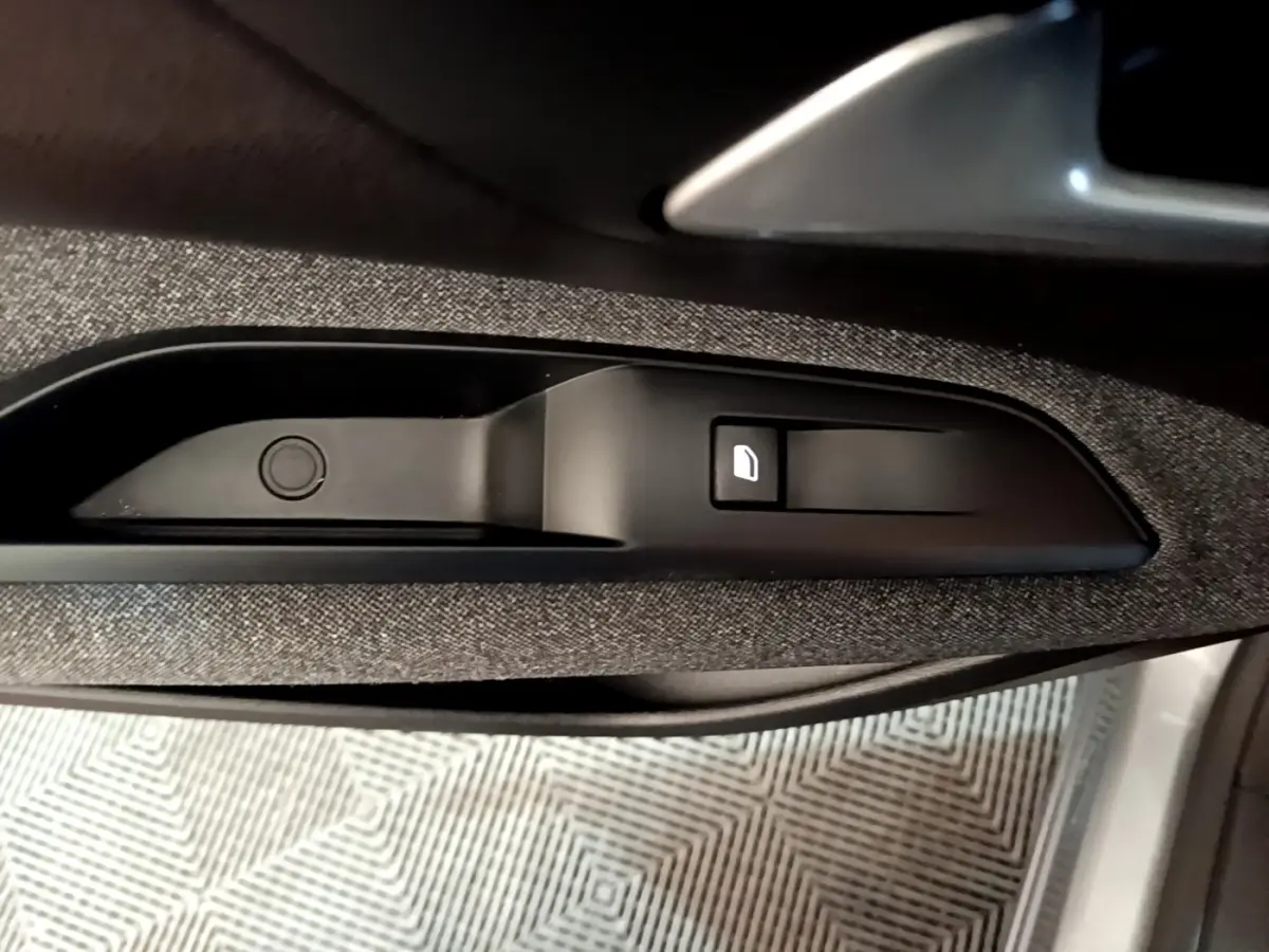 Détail de la poignée intérieure et bouton de verrouillage de porte sur la portière côté conducteur du Peugeot 5008 gris foncé.