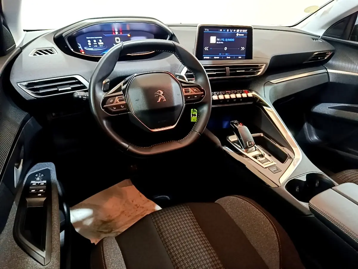 Vue intérieure avant du Peugeot 5008 gris foncé 2020, avec volant cuir compact et écran tactile central.